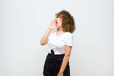 Genç, güzel bir kadın öfkeyle ve yüksek sesle kenardaki boşluğu kopyalamak için bağırıyor. Ağzı beyaz duvara dayalı.