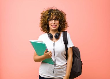 Genç ve güzel bir bayan endişeli, stresli, endişeli ve korkmuş görünüyor. Pembe duvara karşı panikliyor ve dişlerini sıkıyor.