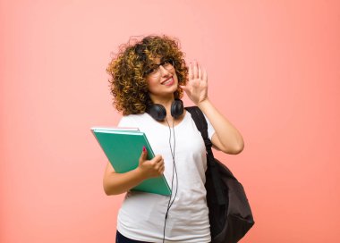 Genç ve güzel bayan, mutlu ve neşeyle gülümseyen, el sallayan, sizi selamlayan, ya da pembe duvara veda eden.