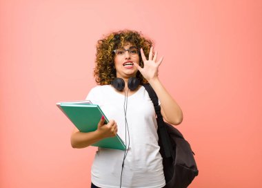 Genç ve güzel bayan kızgın, sinirli ve hayal kırıklığına uğramış görünüyor. Çığlık atıyor. Ya da pembe duvara yaslanmış senin sorunun ne?