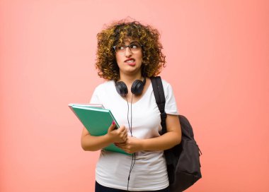 Kafası karışmış, kafası karışmış genç ve güzel bir bayan bir sorunu çözmeye çalışıyor ya da pembe duvara karşı düşünüyor.