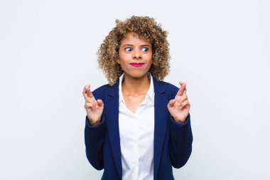 Afro-Amerikan genç kadın endişeyle şans diliyor ve duvarda endişeli bir bakışla iyi şanslar diliyor.