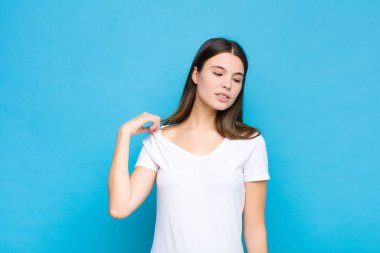 Genç, güzel bir kadın stresli, endişeli, yorgun ve hayal kırıklığına uğramış, gömleğini çekmiş, mavi duvara karşı sorunlu görünüyor.