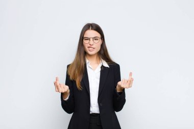 Genç iş kadını kışkırtıcı, agresif ve müstehcen hissediyor, beyaz duvara karşı isyankar bir tavırla orta parmağını hareket ettiriyor.