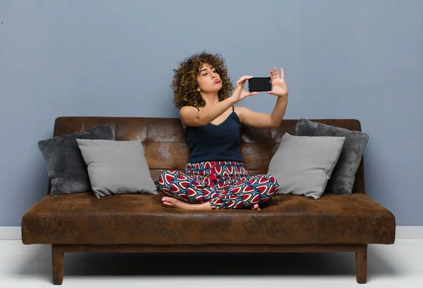 Fiatal csinos nő otthon, mobiltelefonnal, pizsamában — Stock Fotó