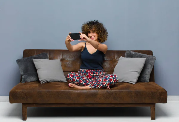 Fiatal csinos nő otthon, mobiltelefonnal, pizsamában — Stock Fotó