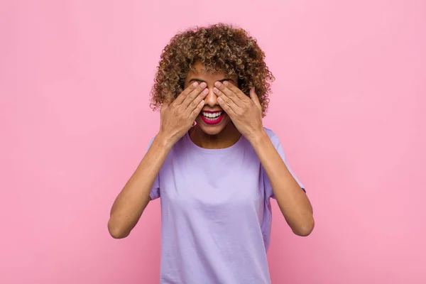 若いアフリカ系アメリカ人の女性は手で目を覆いピンクの壁に対する信じられないほどの驚きを待っています — ストック写真