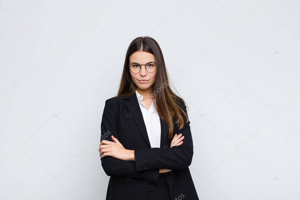 young businesswoman feeling displeased and disappointed, looking serious, annoyed and angry with crossed arms against white wall