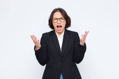 Genç iş kadını öfkeyle bağırıyor, strese giriyor ve ellerini havaya kaldırıp neden beyaz duvara yaslandığımı söylüyor.