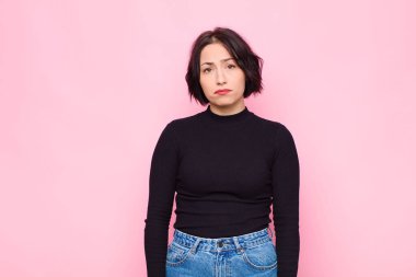 Genç, güzel bir kadın üzgün ve mızmızlanıyor. Mutsuz bir bakışla. Pembe duvara karşı olumsuz ve hayal kırıklığına uğramış bir tavırla ağlıyor.