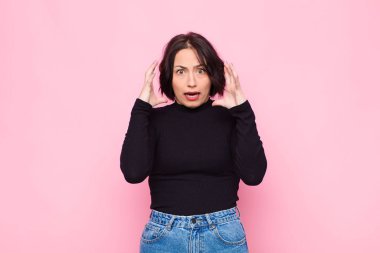 Genç ve güzel bir kadın ellerini havaya kaldırarak çığlık atıyor. Öfkeli, sinirli ve pembe duvara karşı üzgün hissediyor.