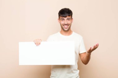 Genç yakışıklı adam mutlu, şaşırmış ve neşeli, olumlu bir tavırla gülümseyen, çözümü ya da fikri bir pankartla gerçekleştiren
