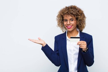 Genç Afrikalı Amerikalı kadın mutlu bir şekilde gülümsüyor, kendini mutlu hissediyor ve fotokopi alanında bir konsept gösteriyor.