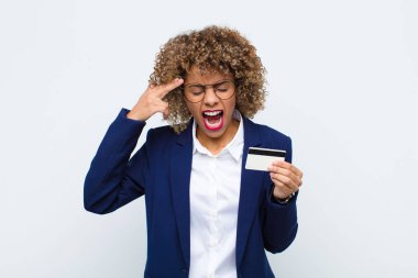 Genç Afro-Amerikan kadın mutsuz ve stresli görünüyor, intihar jesti elinde silah işareti yapıyor, kredi kartıyla kafasını işaret ediyor.
