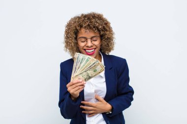 Genç Afrikalı Amerikalı bir kadın komik bir şakaya yüksek sesle gülüyor, mutlu ve neşeli hissediyor, euro banknotlarıyla eğleniyor.