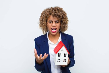 Genç Afrikalı Amerikalı kadın sinirli, sinirli ve hayal kırıklığına uğramış görünüyor. Ev modelinin nesi var?