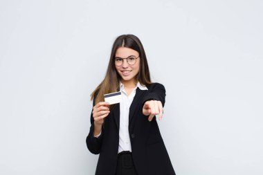 Genç, güzel bir kadın kameraya tatmin olmuş, kendinden emin, dost canlısı bir gülümsemeyle bakıyor, seni kredi kartıyla seçiyor.