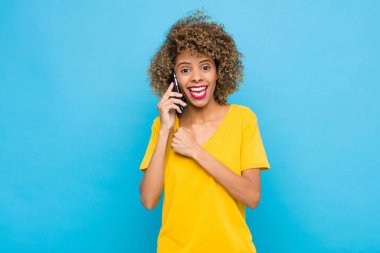 Genç Afrikalı Amerikalı mutlu, pozitif ve başarılı hissediyor, bir meydan okumayla karşılaştığında motive oluyor veya iyi sonuçları cep telefonuyla kutluyor