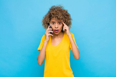 Genç Afrikalı Amerikalı şaşırmış, ağzı açık, şok olmuş, cep telefonuyla yeni bir düşünce, fikir ya da konsept keşfediyor.