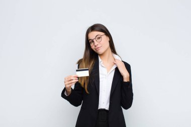 Genç ve güzel bir kadın kibirli, başarılı, pozitif ve gururlu görünüyor, kredi kartıyla kendini işaret ediyor.