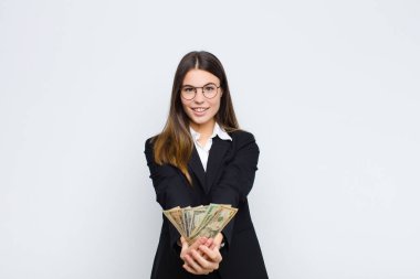 Genç ve güzel bir kadın mutlu bir şekilde gülümsüyor. Sevimli, kendine güvenen, pozitif bakışlı, bir objeyi ya da konsepti banknotlarla sunan.