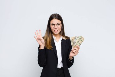 Genç, güzel bir kadın gülümsüyor ve arkadaş canlısı görünüyor. Elleri önde, banknotlarla geri sayıyor.