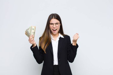 Genç ve güzel bir kadın öfkeli bir ifadeyle ya da yumruklarla bağırarak başarıyı banknotlarla kutluyor.