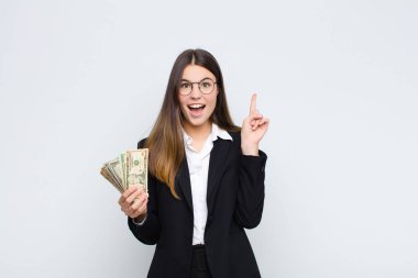 Genç ve güzel bir kadın bir fikri fark ettikten sonra mutlu ve heyecanlı bir dahi gibi hissediyor, neşeli bir şekilde parmağını kaldırıyor, eureka! Banknotlarla