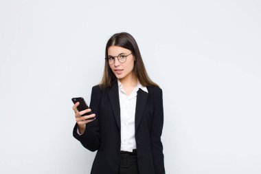 Genç ve güzel bir kadın kafası karışmış görünüyor, sinirsel bir hareketle dudağını ısırıyor, cep telefonuyla sorunun cevabını bilmiyor.