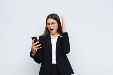 Genç ve güzel bir kadın ellerini havaya kaldırarak bağırıyor. Öfkeli, sinirli, stresli ve cep telefonuyla üzgün.