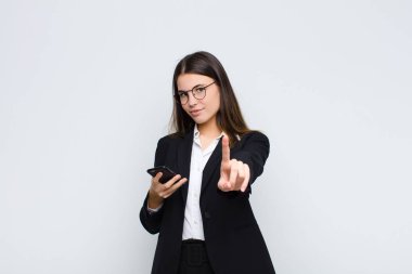 Genç ve güzel bir kadın gururla gülümsüyor ve gururla bir numaralı pozu veriyor. Kendini cep telefonlu bir lider gibi hissediyor.