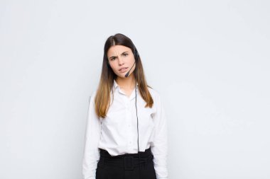 Genç, güzel bir kadın, kulaklıklar ve mikrofonla beklenmedik bir şeye bakan aptal, afallamış bir ifadeyle şaşkın ve şaşkın hissediyor.