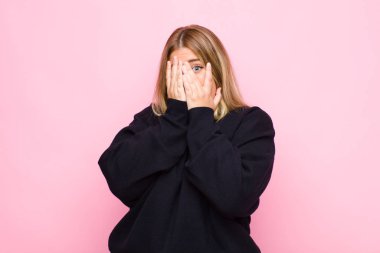 Genç sarışın kadın korkmuş ya da utanmış hissediyordu, dikizliyordu ya da gözleri yarı çıplak bir şekilde duvara bakıyordu.