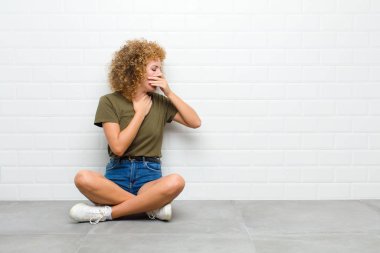 Genç afro bir kadın boğazı ağrıdığı ve grip belirtileri gösterdiği için öksürüp duruyor.