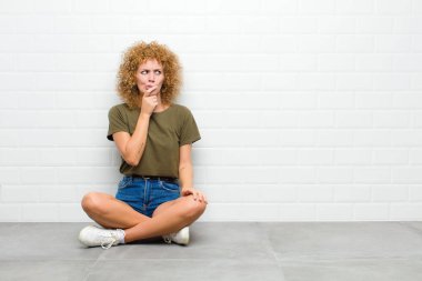 Genç afro kadın düşünüyor, şüpheci ve şaşkın hissediyor, farklı seçeneklerle, hangi kararı vereceğini merak ediyor.