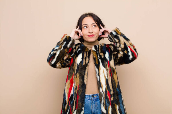 молодая красивая женщина чувствует себя смущенной или сомневающейся, концентрируясь на идее, хорошо думая, пытаясь скопировать пространство сбоку от бежевой стены
