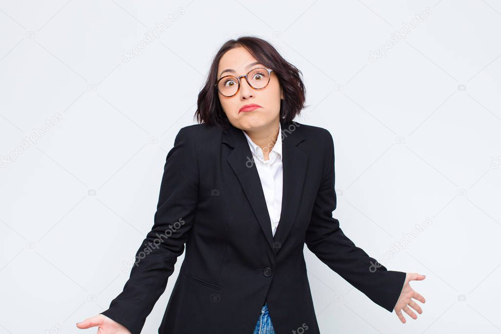 young businesswoman feeling clueless and confused, having no idea, absolutely puzzled with a dumb or foolish look against white wall