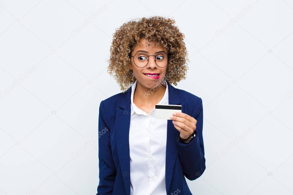 young african american woman looking puzzled and confused, biting lip with a nervous gesture, not knowing the answer to the problem with a credit card