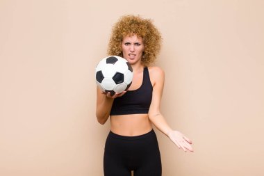 Genç afro kadın şaşkın, şaşkın ve stresli görünüyor, farklı seçenekler arasında merak ediyor, belirsiz bir spor konsepti hissediyor
