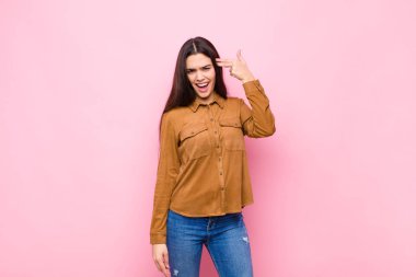 Genç ve güzel bir kadın mutsuz ve stresli görünüyor. İntihar jesti. Elleriyle silah işareti yapıyor.