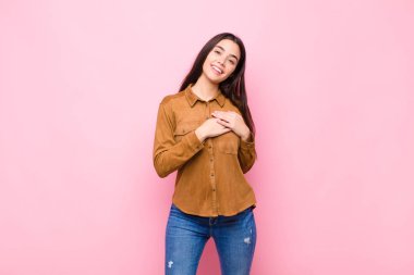 Genç, güzel bir kadın romantik, mutlu ve aşık, neşeyle gülümseyen ve pembe duvara yakın el ele tutuşan