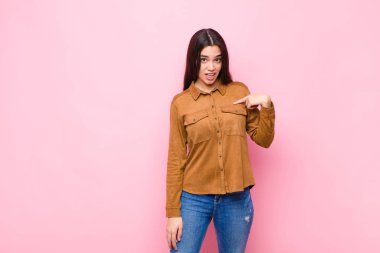 Kafası karışmış, kafası karışmış ve kendine güveni olmayan genç güzel bir kadın kendini gösterip kim olduğumu soruyor, ben mi? Pembe duvara yaslan