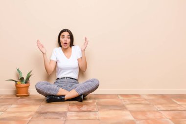 Genç ve güzel bir kadın şok olmuş ve şaşırmış görünüyor, yere oturan inanılmaz bir şey fark edince şaşkınlık içinde çene