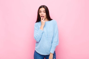 Şaşırmış, gergin, endişeli ya da korkmuş bakışları olan genç, güzel bir kadın. Pembe duvara karşı fotokopi odasına bakıyor.