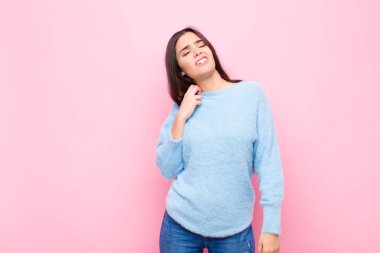 Genç, güzel bir kadın stresli, endişeli, yorgun ve hayal kırıklığına uğramış, gömleğini çekmiş, pembe duvara karşı sorunlu görünüyor.