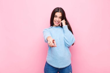 Genç, güzel bir kadın neşeyle gülümsüyor ve kamerayı işaret ediyor. Daha sonra seni arıyor. Telefonda pembe duvara karşı konuşuyor.