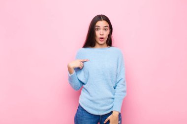 Kafası karışmış, kafası karışmış ve kendine güveni olmayan genç güzel bir kadın kendini gösterip kim olduğumu soruyor, ben mi? Pembe duvara yaslan