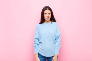 Genç, güzel bir kadın şok olmuş, mutlu, şaşkın ve şaşırmış hissediyor. Ağzı açık pembe duvara bakıyor.