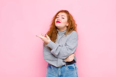 Genç kızıl saçlı kadın kafası karışık ve cahil, şüpheli bir açıklamayı merak ediyor ya da pembe duvara karşı düşüncelerini merak ediyor.