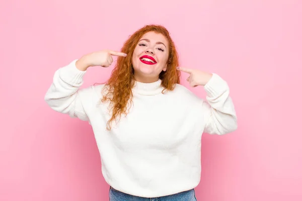 Junge Rote Kopffrau Lächelt Selbstbewusst Und Zeigt Auf Ihr Eigenes — Stockfoto